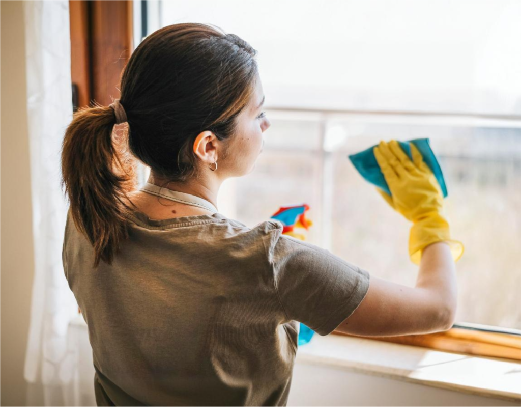 Cura Maids cleaner wiping a window, highlighting top considerations for hiring house cleaning services in Raleigh.